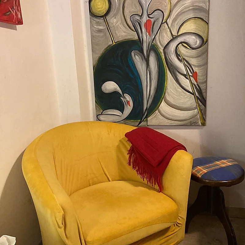 Poltrona gialla dello studio con plaid rosso e quadri alle pareti